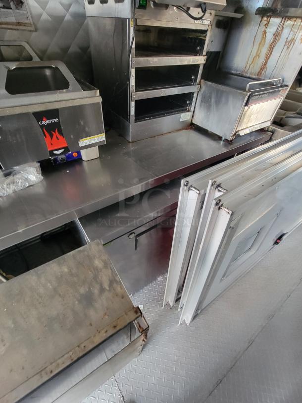 Interior of a 2022 Titanium Cargo 28' food trailer featuring a Cayenne cooking unit, Crisp 'N Hold station, and stainless steel setup.