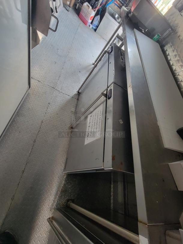 Interior view of 2022 Titanium Cargo 28' food trailer with stainless steel counters, commercial kitchen equipment, and storage.