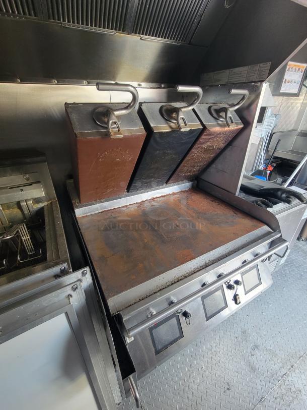 2022 28' Titanium Cargo Food Trailer interior with commercial gas griddle, part of high-volume fried food setup.