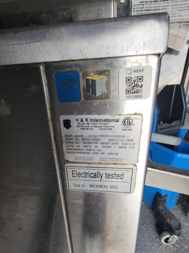 H & K International stainless steel equipment tag with NSF and ETL markings, indicating a 34" meat freezer. Serial: 8032831-031. Electrically tested.