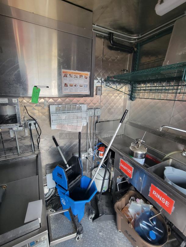 Interior of 2022 Titanium 28' food trailer showing professional kitchen setup, mop bucket, and labeled sanitation stations.