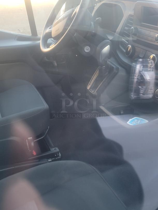 Interior of 2021 Ford Transit 350 Cargo Van, showcasing seats, dashboard, and gear shift. Near-new condition, low mileage.