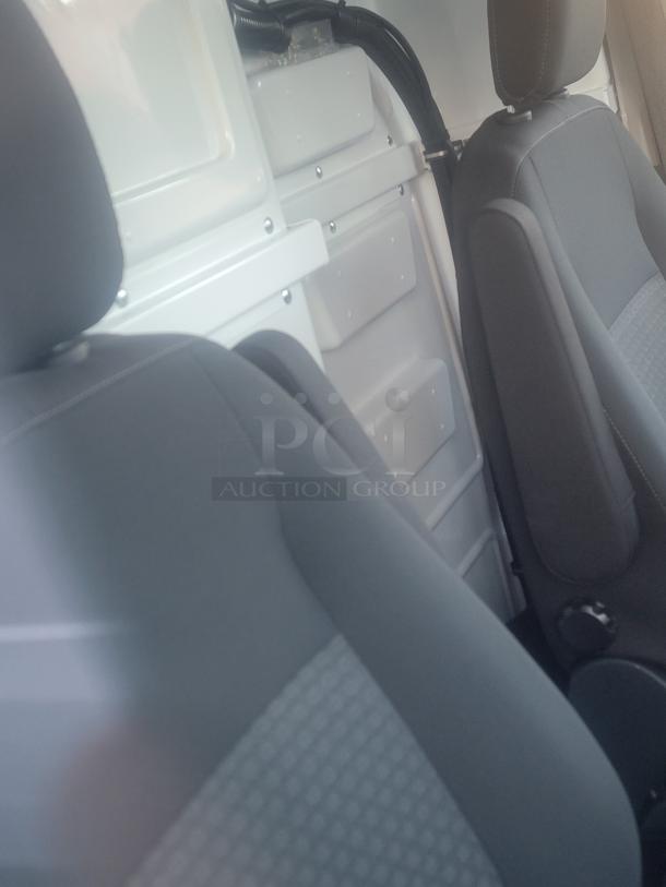 Interior view of 2021 Ford Transit 350 Cargo Van showing front seats and solid factory partition. Clean and near-new condition.