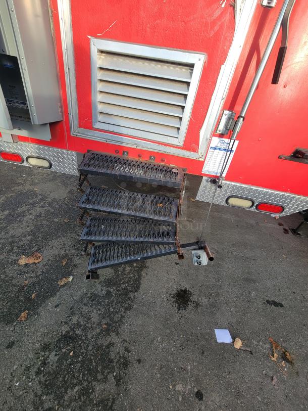 Red exterior of a 2021 Texino 28-foot food trailer with side vent, foldable black metal steps, and a visible power panel.