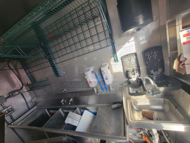 2021 Texino 28-foot food trailer interior with stainless steel counters, sink, dispensers, and shelving, ready for high-volume use.