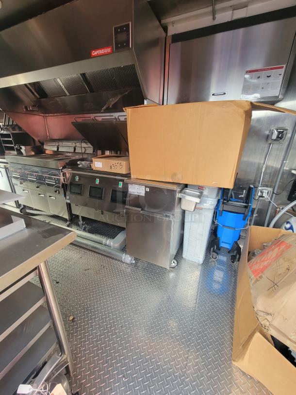 2022 Rock Solid 28' food trailer interior with high-end, unused commercial kitchen equipment, including CaptiveAire hood.