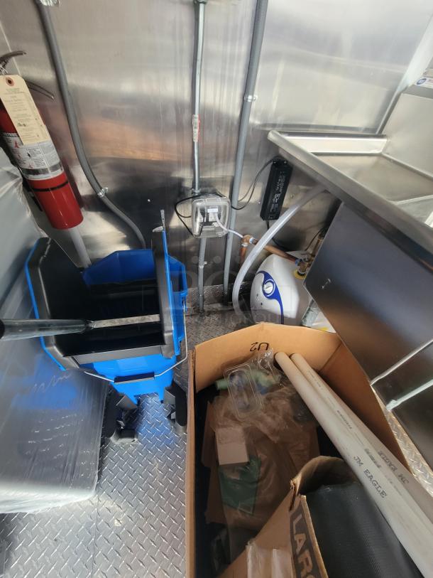 2022 Rock Solid 28' food trailer interior with new equipment, mop bucket, and sink. Pristine, unused condition.