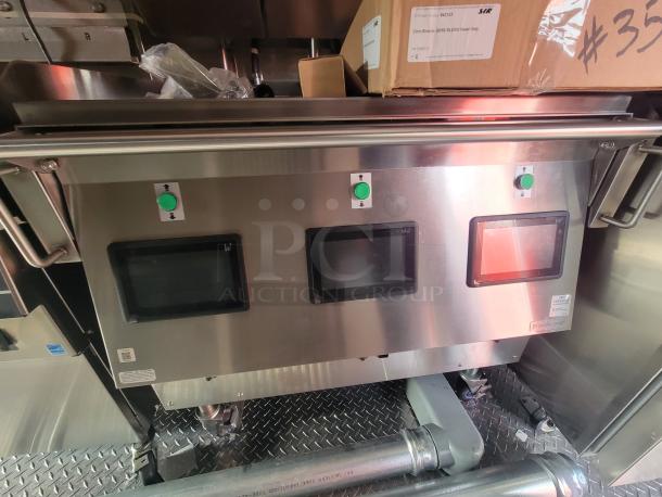 Stainless steel control panel in a new 2022 Rock Solid 28' food trailer, featuring touchscreen monitors and green control buttons.