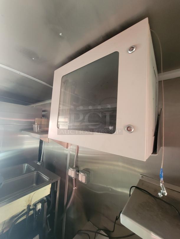 2022 Rock Solid 28' food trailer interior, featuring a pristine high-end commercial kitchen setup, unused, with stainless steel surfaces and electrical outlets visible.