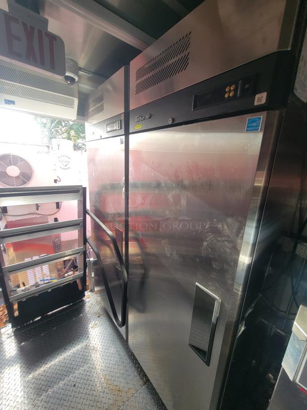 2022 Rock Solid 28' food trailer interior with Turbo Air stainless steel fridge, pristine condition, equipped for high-volume cooking.