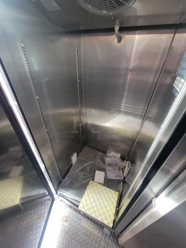 Interior of unused 2022 Rock Solid 28' food trailer. Pristine metal walls, protective packaging, and commercial-grade shelving.