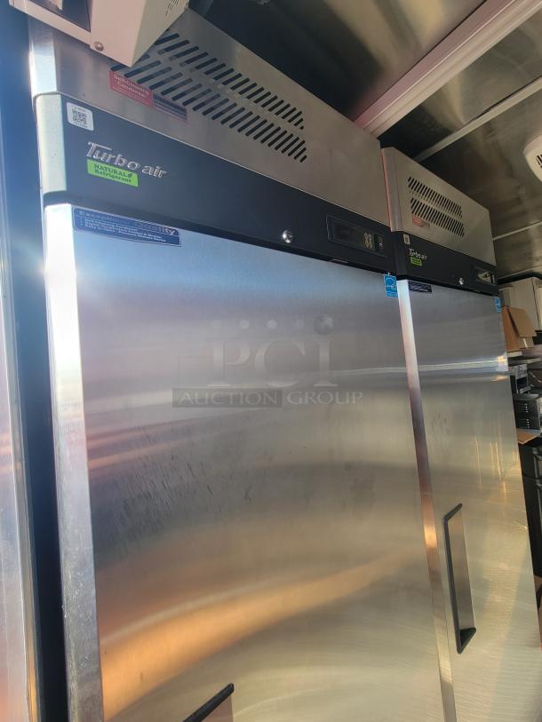2021 Titanium 28' food trailer interior with unused Turbo Air stainless steel refrigeration units, protective materials intact.