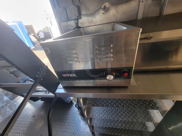 Interior of a 2021 Titanium 28' food trailer featuring new, unused Winco appliance with factory protective material intact.