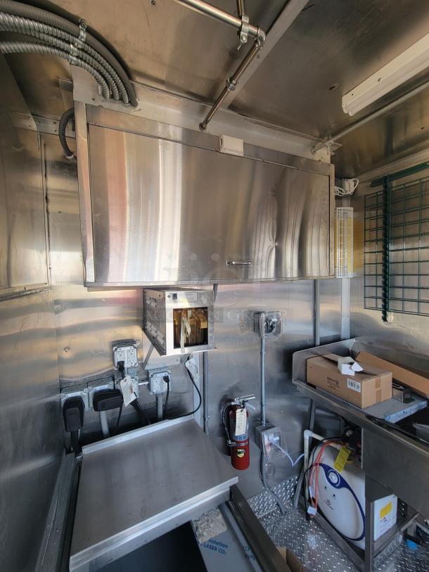 2021 Titanium 28' food trailer interior, unused, pristine condition, professional-grade kitchen equipment, protective materials visible.