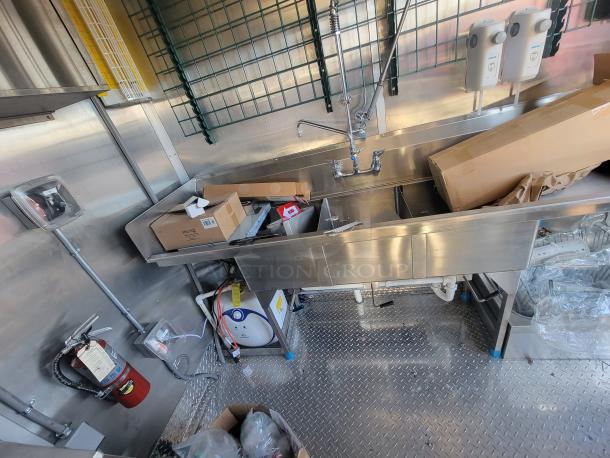 2021 Titanium 28' food trailer interior, showcasing unused, professional-grade kitchen equipment with protective coverings.