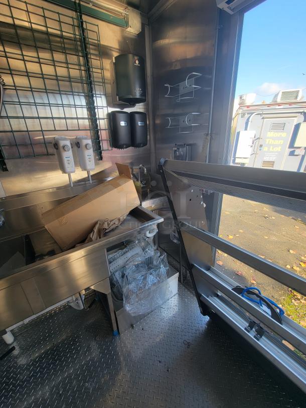 2021 Titanium 28' food trailer interior, commercial-grade, unused equipment, stainless surfaces, protective coverings visible.