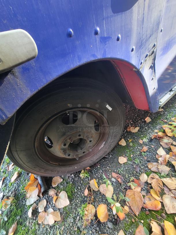 Close-up of a wheel on a 2003 Chevrolet Workhorse P24 food truck, showing wear and some rust on the rim.
