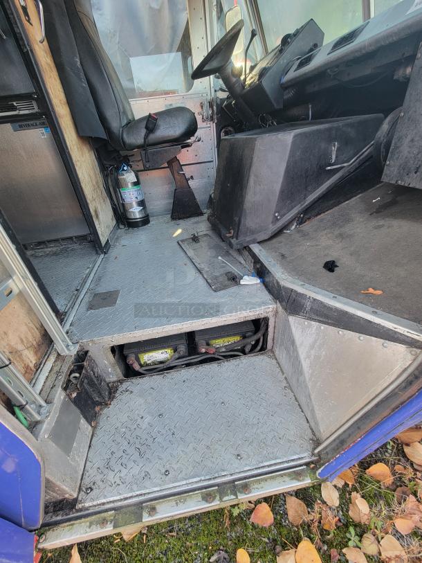 2003 Workhorse Diesel Food Truck interior, showing the driver’s area with a manual seat, fire extinguisher, and under-seat storage.