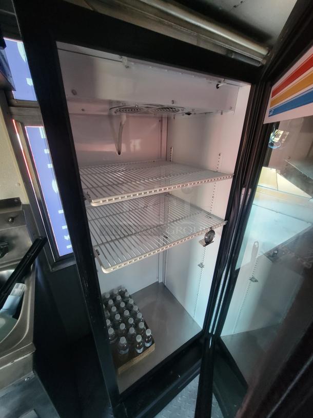 Interior of a 2003 Workhorse food truck showing a commercial-grade refrigerator with three shelves and bottled water.