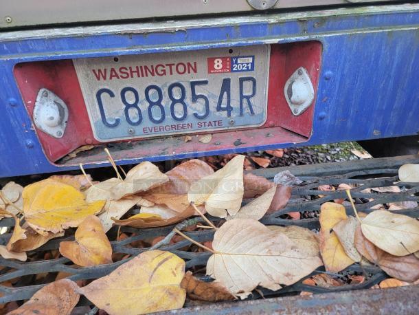 Blue 2003 Chevrolet P24 Workhorse food truck with Washington license plate C88854R, surrounded by fallen leaves.