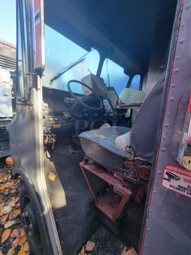 Interior view of a 1973 International Step Van, showing smoke damage. Features driver's seat, steering wheel, and control panel.