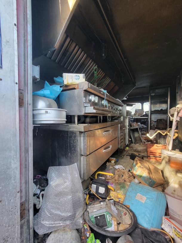 1973 International Step Van with fire-damaged stainless steel kitchen equipment. Smoke damage visible. Ideal for salvage or restoration.