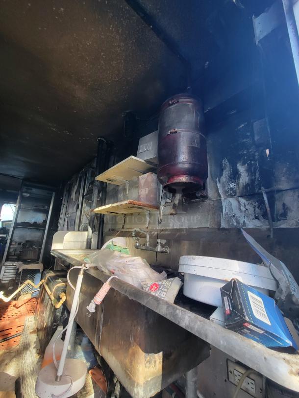 1973 International Step Van with fire-damaged kitchen equipment. Features include stainless steel counters and sink. Restoration project.