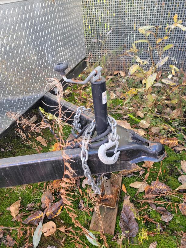 2021 Quality 24' trailer hitch and chain on grassy ground, diamond plate siding visible. Fully equipped electric kitchen.