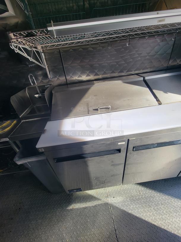 2021 24' Quality Trailer interior with stainless steel electric appliances, sink, storage shelves, and work counters.