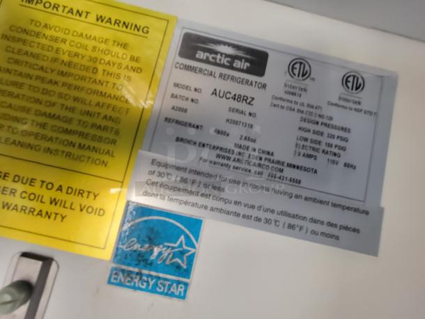 Label on Arctic Air commercial refrigerator model AUC48RZ. Yellow warning suggests regular condenser coil maintenance. Energy Star rated.