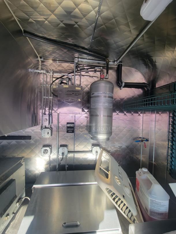 Interior of a 2021 16' high-end commercial food trailer showing stainless steel appliances, wiring, and storage space.