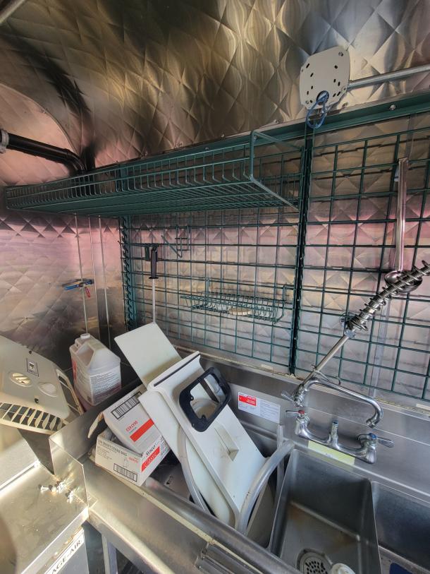 2021 16' Quality food trailer interior, featuring stainless steel sink, shelving, and Arctic Air conditioner, excellent condition.