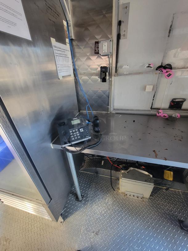 16' commercial food trailer interior with stainless steel surfaces, phone setup, and visible wiring. Used, well-maintained.