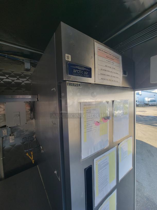 High-end 2021 16' food trailer interior, featuring Arctic Air commercial freezer with inspection labels, ideal for mobile kitchen use.