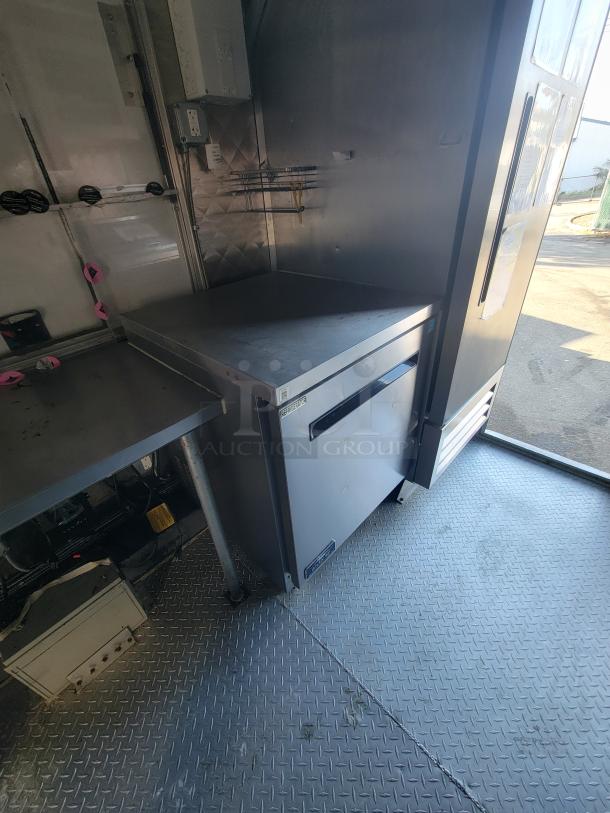 16' commercial food trailer interior with stainless steel prep area, Arctic Air refrigeration, and diamond plate flooring.