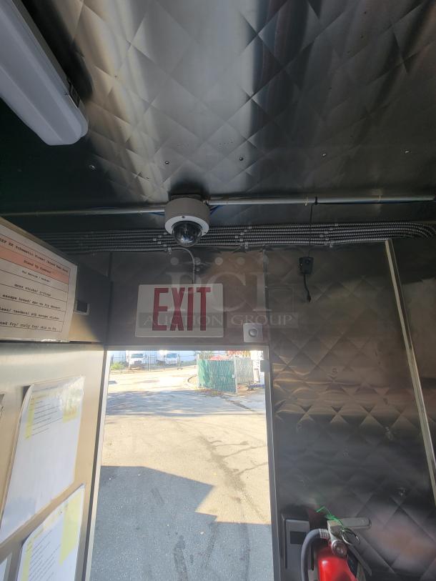 Interior of a 2021 Quality 16' Commercial Food Trailer. Features stainless steel walls, security camera, and exit sign.