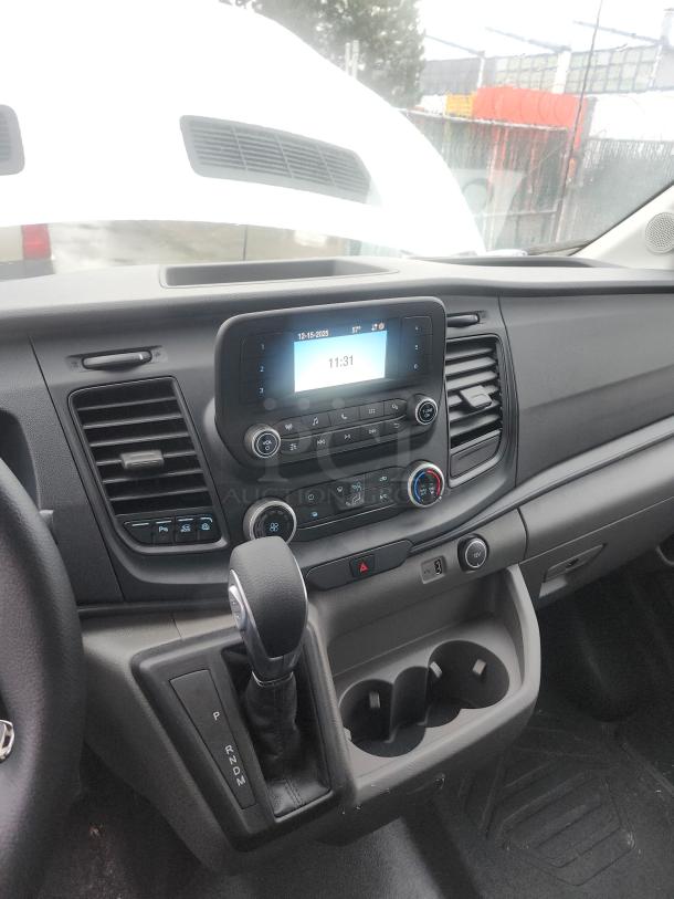 Interior of a 2020 Ford Transit 350 Cargo Van showing dashboard, gearshift, and modern infotainment system display.