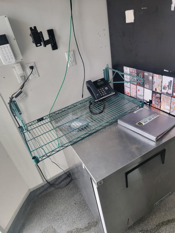 Inside view of 2021 SDG 8.5' x 20' concession trailer, featuring metal shelf, phone, secure keypad, and stainless surface.