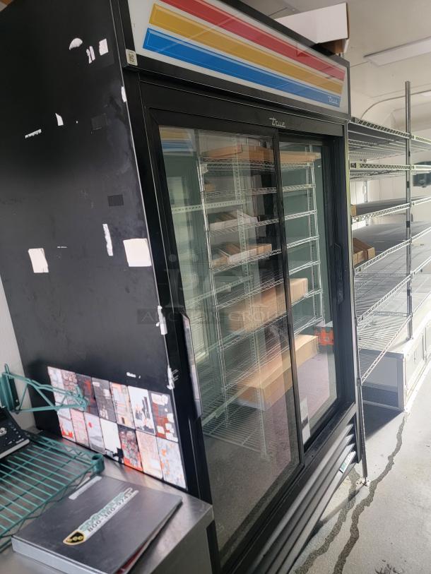 Interior of a 2021 SDG 8.5' x 20' food concession trailer featuring a glass door refrigerator, wire shelving, and vending materials.