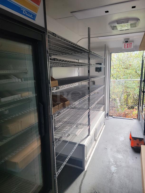 Interior of 2021 SDG 8.5' x 20' food concession trailer, featuring stainless steel racks and storage, designed for frozen goods.