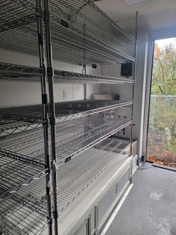 Interior view of 2021 SDG 8.5' x 20' food concession trailer, featuring metal shelving, sink, and clean, modern design.