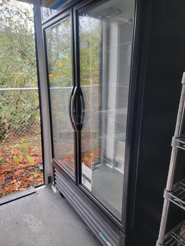 Inside view of a fully-equipped 2021 SDG 8.5' x 20' food concession trailer showing a double-door commercial refrigerator adjacent to shelving.