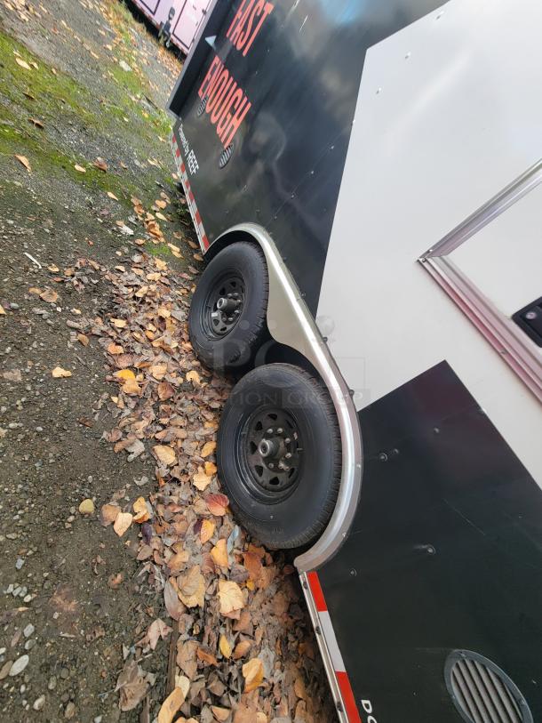 2021 Diamond Cargo 24' mobile kitchen trailer, side view, showing dual wheels, autumn leaves on the ground.