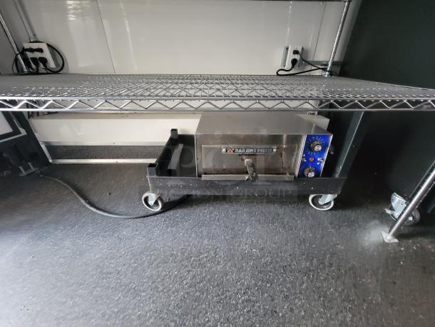 Bakers Pride electric oven on wheels inside a 2021 Diamond 24' mobile kitchen trailer. Stainless steel shelving above.