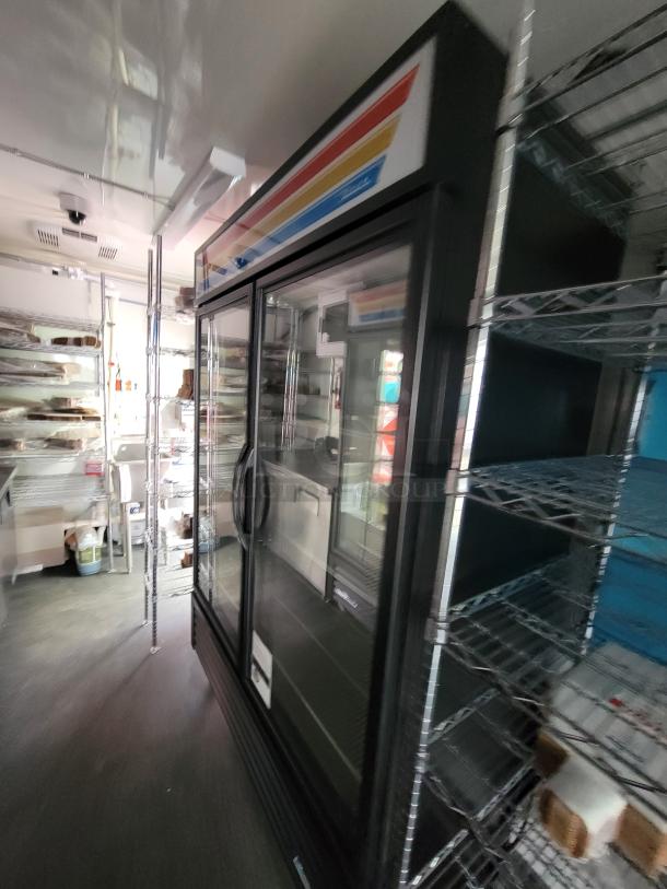 Interior of 2021 Diamond 24' mobile kitchen trailer, featuring True Refrigeration units and stainless steel shelving.