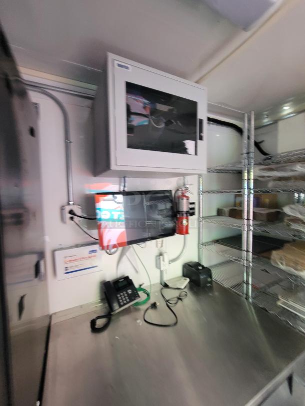 Interior of 2021 Diamond Cargo 24' mobile kitchen trailer, showcasing stainless steel prep counters, shelving, and phone system.