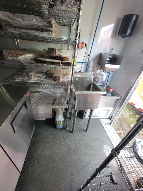 2021 Diamond Cargo 24' mobile kitchen interior with stainless steel counters, multi-compartment sinks, and shelving.