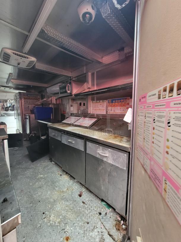 2019 Rock Solid 24' food trailer interior; features a commercial prep base, overhead exhaust hood, and commercial lighting.