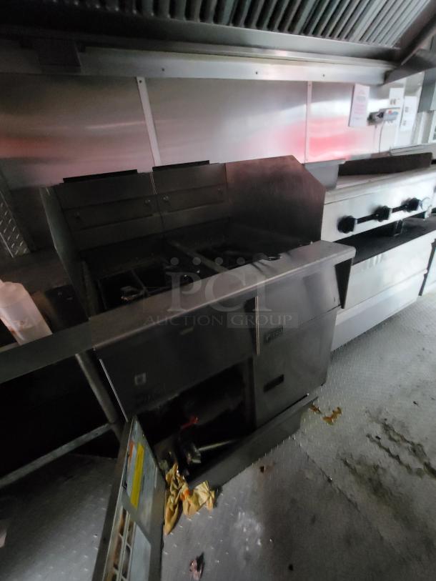 2019 Rock Solid Cargo 24' food trailer interior, showing cookline with gas fryer, range, and exhaust hood. Clean, functional condition.