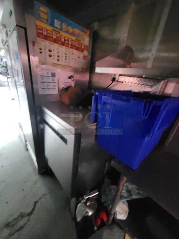 2019 Rock Solid 24' food trailer interior showing prep area with blue storage bin and commercial fridge.